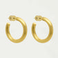 Gold hoop earrings on a light beige background