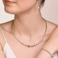 Woman wearing a pearl necklace, earrings, and bracelet on a beige background