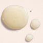 Close-up of three droplets of a light-colored liquid on a beige background