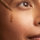Close-up of a woman applying brown concealer to her face with a brush.