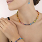 Model wearing the GeoCUBE collection in the colour rainbow featuring a necklace, a bracelet and earrings.