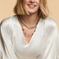 View of a blonde model in a white shirt wearing the GeoCUBE onyx and gold pearl fusion necklace.