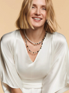 View of a blonde model in a white shirt wearing the GeoCUBE onyx and gold pearl fusion necklace.