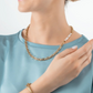 A model wearing a gold chain necklace with pearl accents on the side