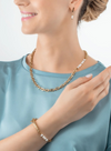 A model wearing a gold chain necklace with pearl accents on the side