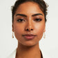 Close-up of a woman wearing gold earrings against a white background