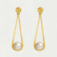 Gold earrings with pearl drops on a light gray background