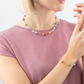 Model wearing the GeoCUBE set in the colour aqua and apricot featuring a necklace, earrings and a bracelet.