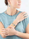 Model wearing the turquoise GeoCUBE collection featuring a necklace, earrings and a bracelet