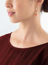 Model wearing the red and gold GeoCUBE earrings wearing a dark red shirt