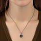 Necklace with a pendant worn by a person, focusing on the necklace and its design.