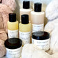 Collection of baby care products including bottles and a jar on a soft surface.