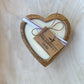 Heart-shaped candle with a wooden frame on a light wooden surface