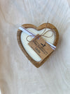 Heart-shaped candle with a wooden frame on a light wooden surface