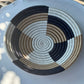 Round woven basket with concentric circle pattern on a white surface