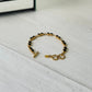 Gold bracelet with black beads on a light wooden surface