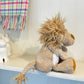 Plush lion toy on a shelf with a colorful plaid blanket in the background