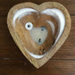 Heart-shaped wooden coaster with a white ceramic heart on a wooden surface