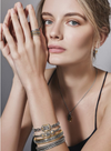 Model posing with a stack of 4 silver bracelets on her arm