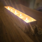Rectangular wooden candle holder with lit candles on a wooden surface