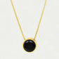 Gold necklace with a black gemstone pendant on a light gray background