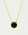 Gold necklace with a black gemstone pendant on a light gray background