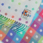 Colourful polka dot blanket with a visible brand label on a white background
