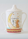 Ceramic cup with a cartoon design of a bunny on a crescent moon, on a white background