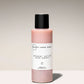 Pink shower scrub bottle with black cap on a gradient background