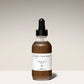Bottle of face oil with a dropper on a beige background